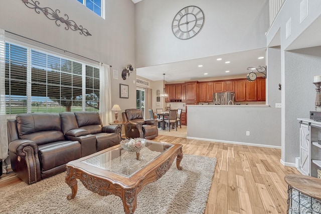 living room with light hardwood / wood-style flooring, a high ceiling, and a healthy amount of sunlight