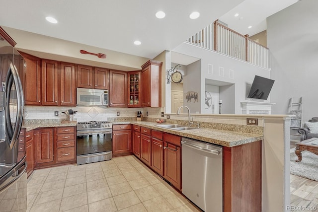 kitchen featuring appliances with stainless steel finishes, kitchen peninsula, light tile patterned floors, backsplash, and sink