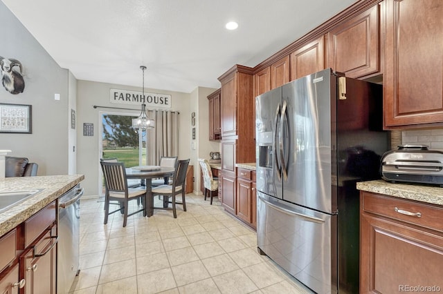 kitchen featuring tasteful backsplash, light tile patterned flooring, appliances with stainless steel finishes, hanging light fixtures, and light stone countertops