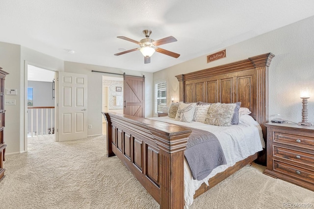 bedroom with light carpet, a barn door, and ceiling fan