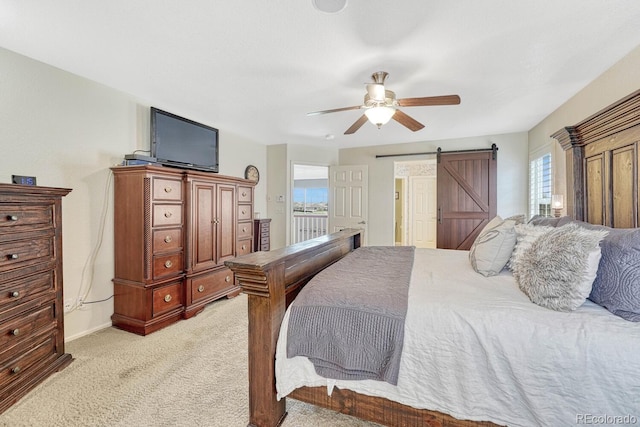 carpeted bedroom featuring ceiling fan and a barn door