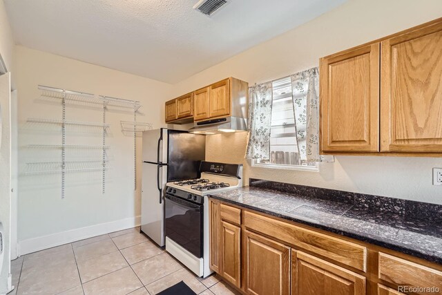 kitchen featuring white range with gas stovetop, a textured ceiling, and light tile patterned flooring