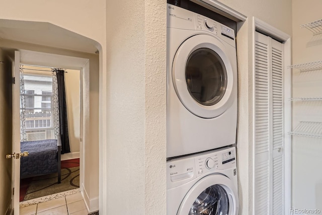 laundry room with stacked washer / drying machine and light tile patterned floors