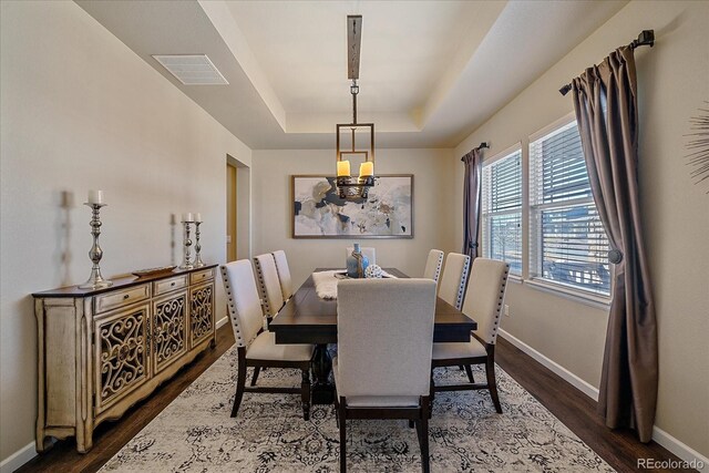 12590 Valentia St, Thornton, CO 80602 - dining area with a chandelier, a tray ceiling, dark wood-style flooring, and baseboards