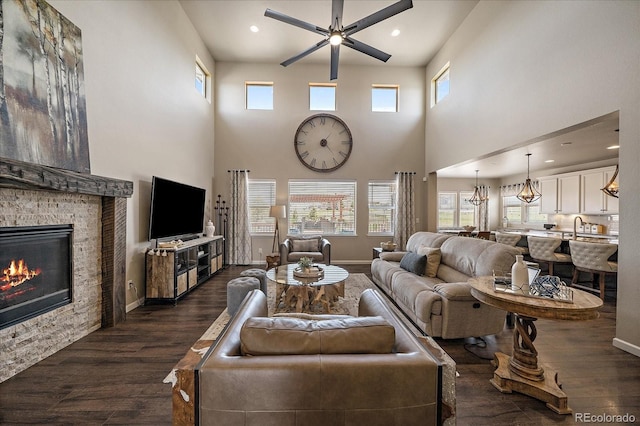 12590 Valentia St, Thornton, CO 80602 - living area with dark wood-style flooring, a high ceiling, a stone fireplace, ceiling fan, and recessed lighting