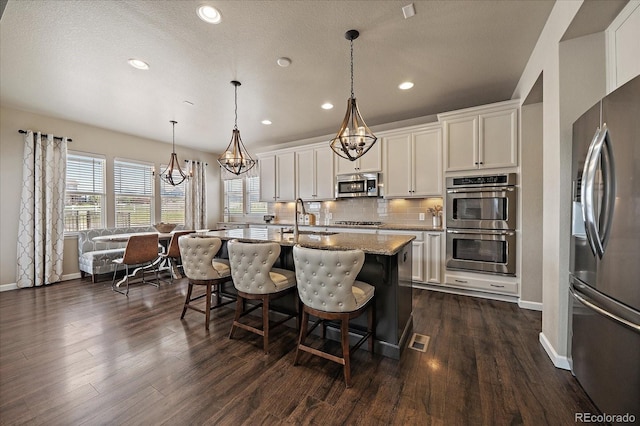 12590 Valentia St, Thornton, CO 80602 - kitchen with appliances with stainless steel finishes, recessed lighting, tasteful backsplash, white cabinetry, and a breakfast bar