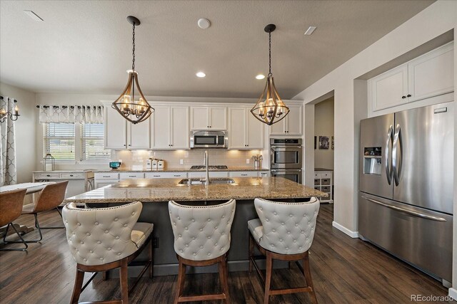 12590 Valentia St, Thornton, CO 80602 - kitchen with appliances with stainless steel finishes, a chandelier, recessed lighting, dark wood-style floors, and tasteful backsplash