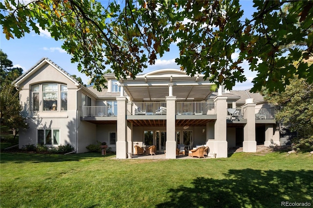 rear view of house featuring a yard, stucco siding, an outdoor living space, and a patio