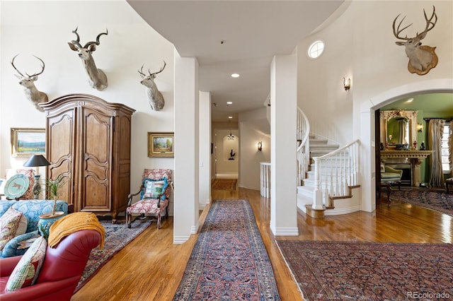corridor featuring light wood-style floors, arched walkways, and stairs