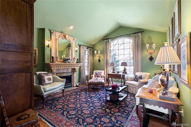 living area featuring lofted ceiling, a fireplace with raised hearth, and wood finished floors