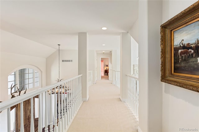corridor with lofted ceiling, baseboards, visible vents, and light colored carpet