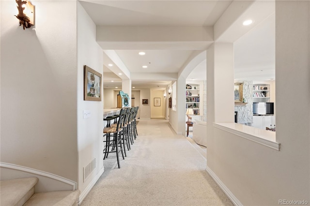 corridor featuring visible vents, baseboards, arched walkways, light colored carpet, and recessed lighting