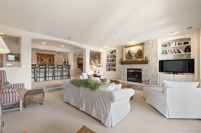 living area with recessed lighting, a stone fireplace, visible vents, and built in features