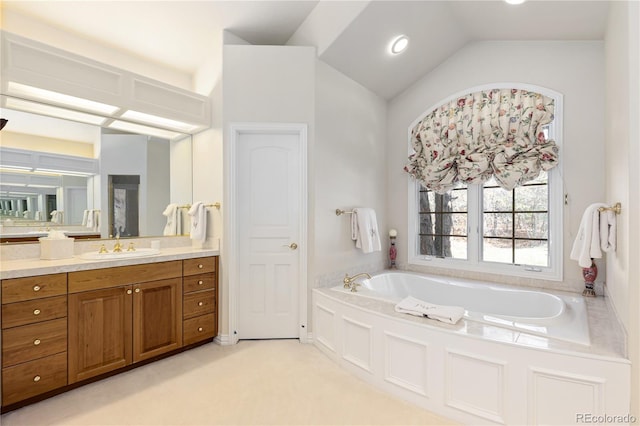 bathroom with lofted ceiling, a garden tub, and vanity