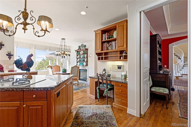 kitchen with built in study area, brown cabinets, open shelves, a chandelier, and white gas stovetop