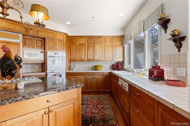kitchen with a sink, white appliances, recessed lighting, decorative backsplash, and tile counters