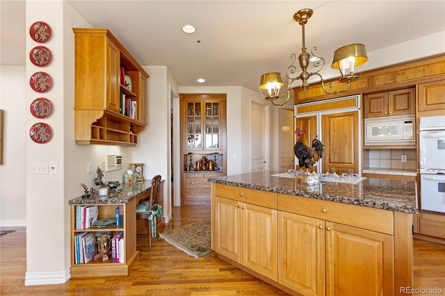kitchen featuring built in appliances, open shelves, light wood-type flooring, recessed lighting, and an inviting chandelier