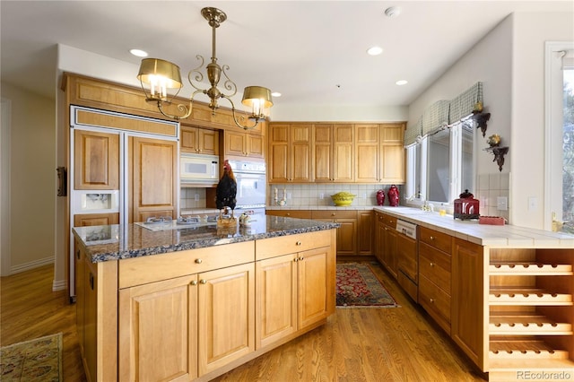 kitchen with wood finished floors, built in appliances, decorative backsplash, a kitchen island, and recessed lighting