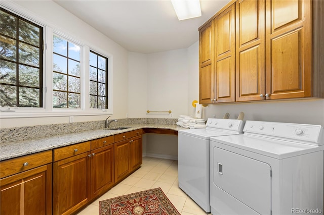 laundry room featuring light tile patterned floors, a sink, washing machine and dryer, and cabinet space