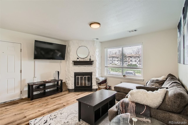 living area featuring a fireplace, visible vents, and wood finished floors