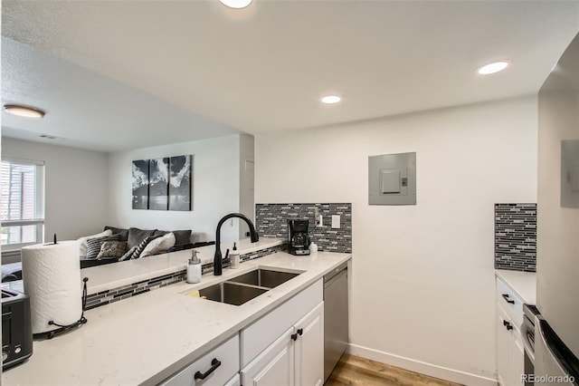 kitchen with electric panel, dishwasher, decorative backsplash, and a sink