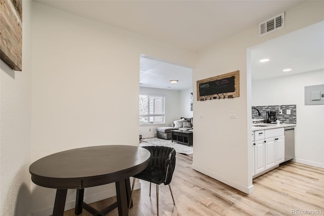 corridor featuring baseboards, light wood-style floors, visible vents, and a sink