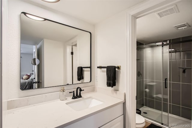 bathroom with toilet, vanity, visible vents, and a shower stall