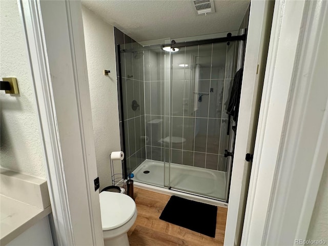 10785 W 63rd Pl Unit 108, Arvada, CO 80004 - full bath featuring toilet, a stall shower, a textured wall, wood finished floors, and a textured ceiling