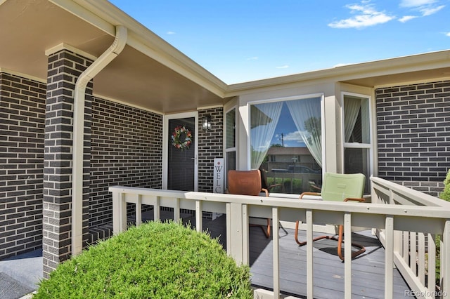 doorway to property featuring brick siding and a wooden deck