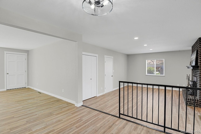 unfurnished living room with wood finished floors, baseboards, recessed lighting, and a fireplace