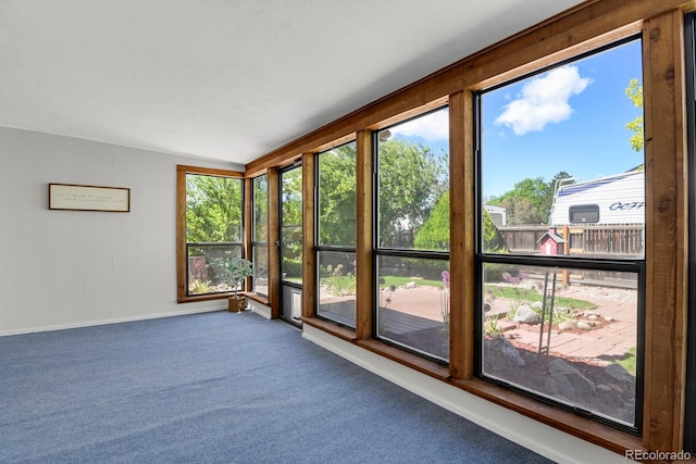unfurnished sunroom with carpet flooring and baseboards
