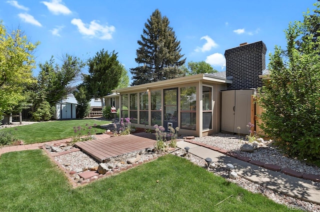 view of green lawn featuring a sunroom, an outdoor structure, and a shed