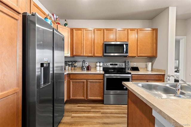 kitchen featuring appliances with stainless steel finishes, light hardwood / wood-style flooring, and sink