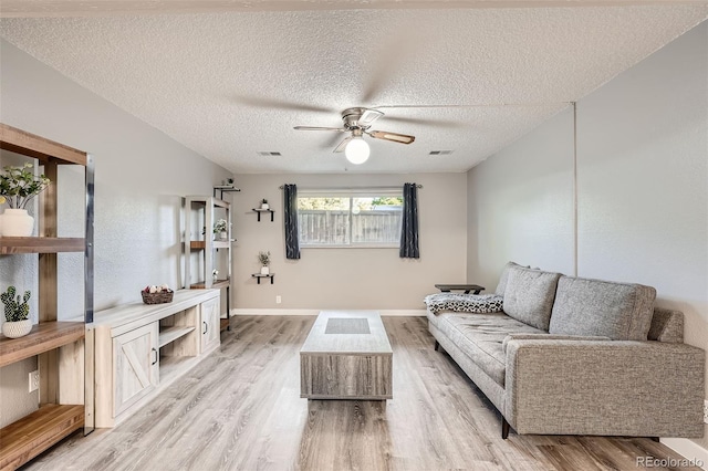 living room with a textured ceiling, ceiling fan, and light hardwood / wood-style flooring