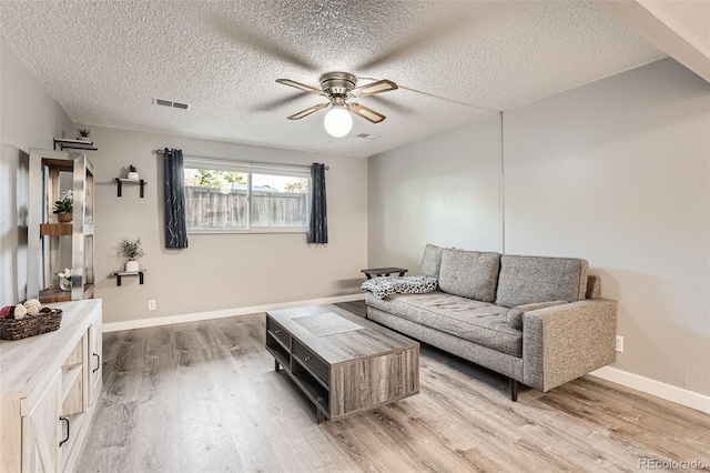 living room with ceiling fan, a textured ceiling, and hardwood / wood-style flooring