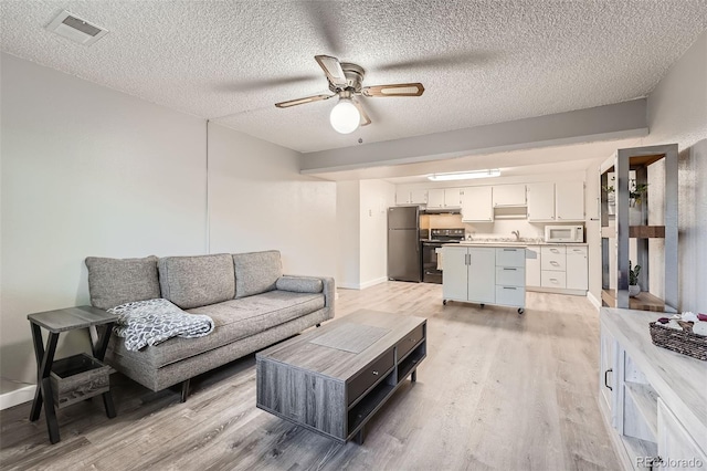 living room with sink, a textured ceiling, ceiling fan, and light hardwood / wood-style flooring