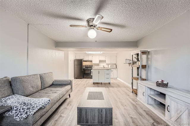 living room featuring light wood-type flooring, ceiling fan, and a textured ceiling