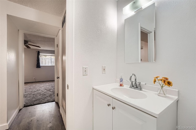 bathroom with hardwood / wood-style flooring, a textured ceiling, ceiling fan, and vanity