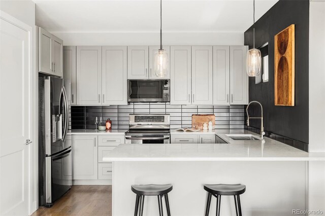 1457 Yates St, Denver, CO 80204 - kitchen featuring stainless steel appliances, a peninsula, a breakfast bar, decorative backsplash, and light countertops