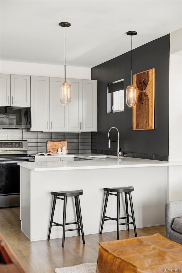 1457 Yates St, Denver, CO 80204 - kitchen with black microwave, stainless steel electric range oven, a breakfast bar area, and light wood-style flooring