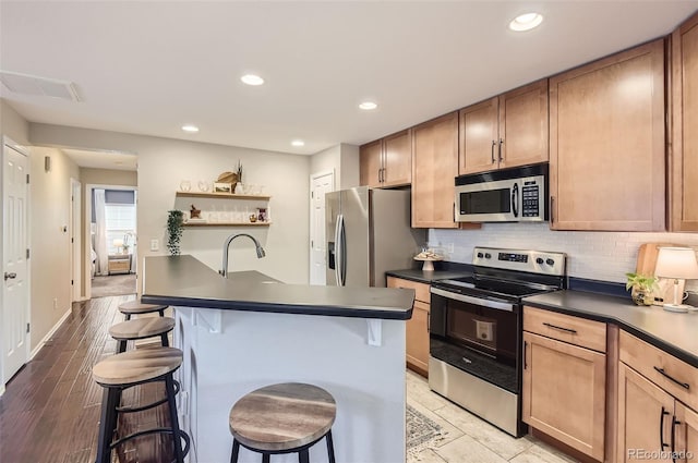 kitchen with a kitchen breakfast bar, sink, light wood-type flooring, and stainless steel appliances