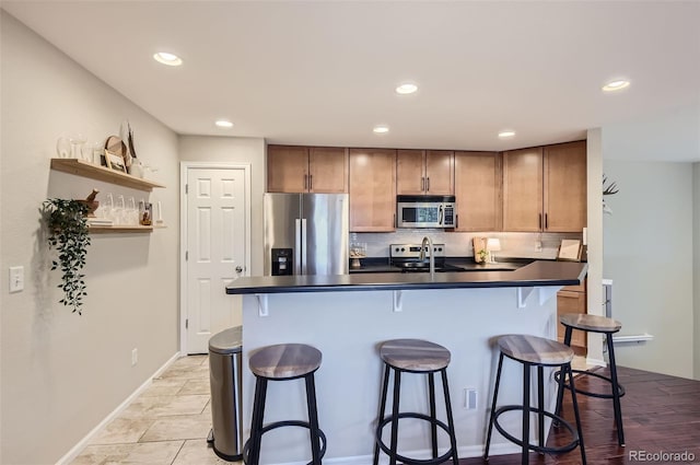 kitchen featuring a kitchen bar, stainless steel appliances, a center island with sink, and sink