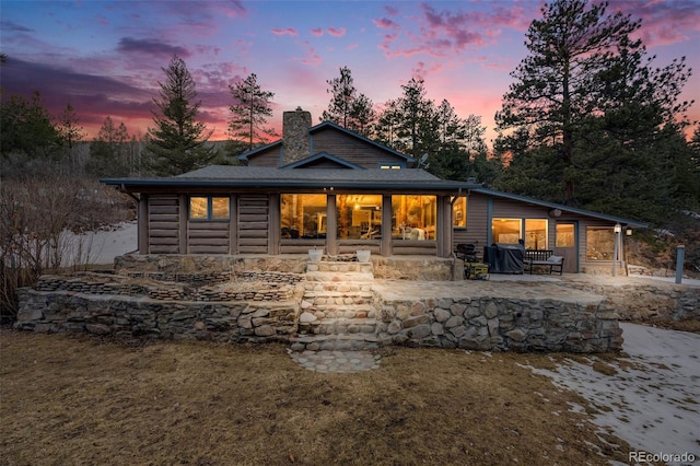 11531 S Deer Creek Rd, Littleton, CO 80127 - back of house at dusk featuring a chimney and a patio
