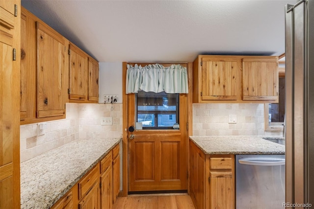 11531 S Deer Creek Rd, Littleton, CO 80127 - kitchen featuring stainless steel dishwasher, tasteful backsplash, light stone counters, and light wood-style flooring