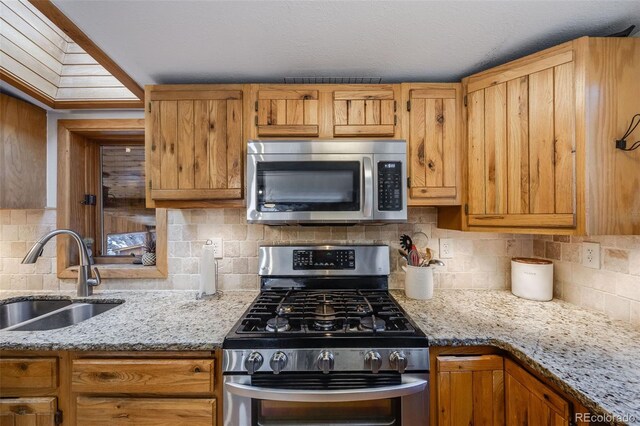 11531 S Deer Creek Rd, Littleton, CO 80127 - kitchen featuring stainless steel appliances, tasteful backsplash, light stone counters, and brown cabinets