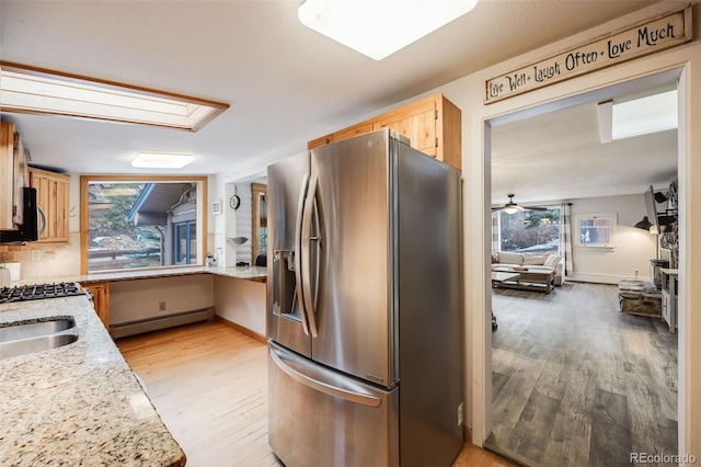 11531 S Deer Creek Rd, Littleton, CO 80127 - kitchen with appliances with stainless steel finishes, a baseboard heating unit, light wood-style floors, and plenty of natural light