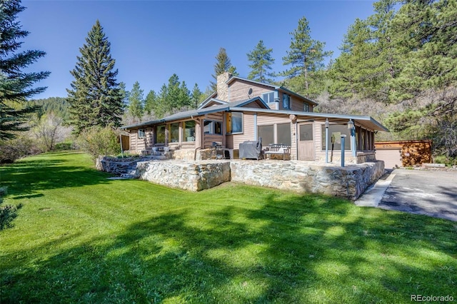 11531 S Deer Creek Rd, Littleton, CO 80127 - view of front of property featuring a sunroom, a chimney, a front lawn, a garage, and asphalt driveway