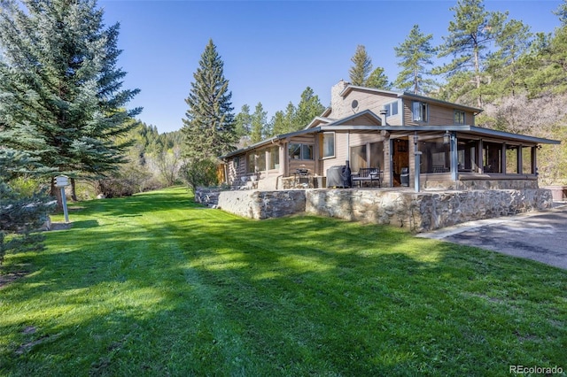 11531 S Deer Creek Rd, Littleton, CO 80127 - view of front facade with a sunroom, a front yard, a patio area, and a chimney