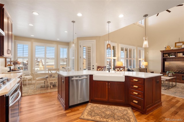 kitchen with pendant lighting, dishwasher, a center island, sink, and light wood-type flooring