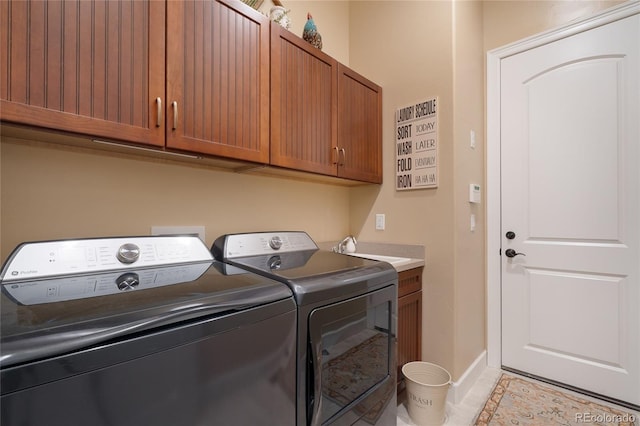 washroom featuring washing machine and dryer, light tile patterned floors, and cabinets